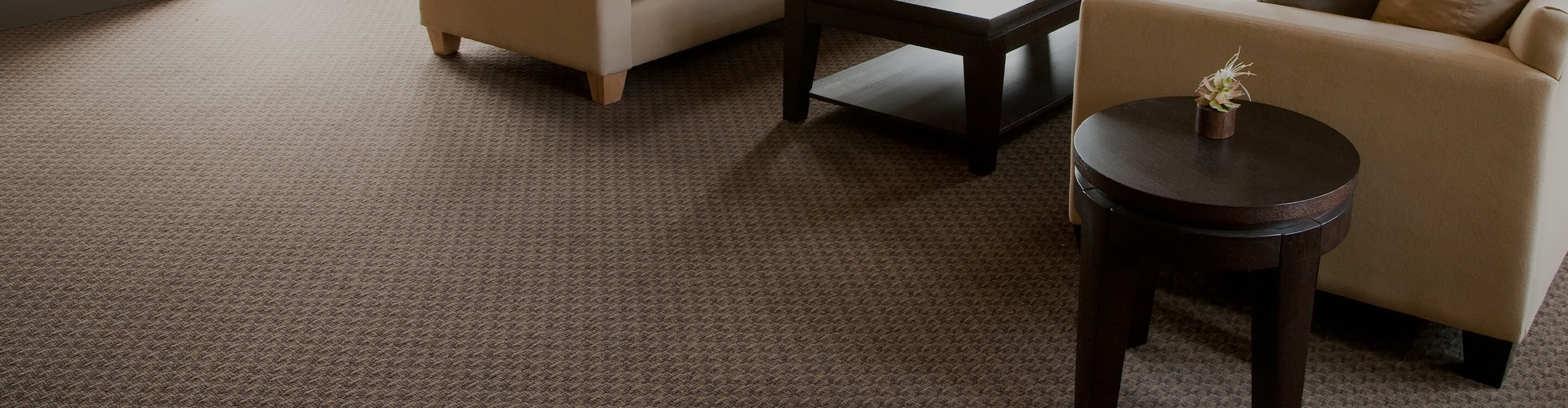 A warm living room with patterned carpet and tan furniture.